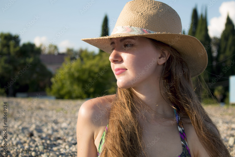 Portrait of young and beautiful woman in hat on a sunny day