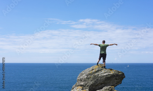 Man on top of rock, looking at sea