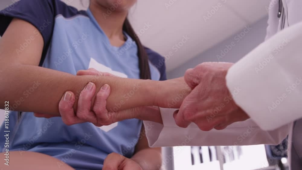 Close up of a senior doctor examining young hispanic athlete's wrist Close up of a senior doctor examining young hispanic athlete's wrist