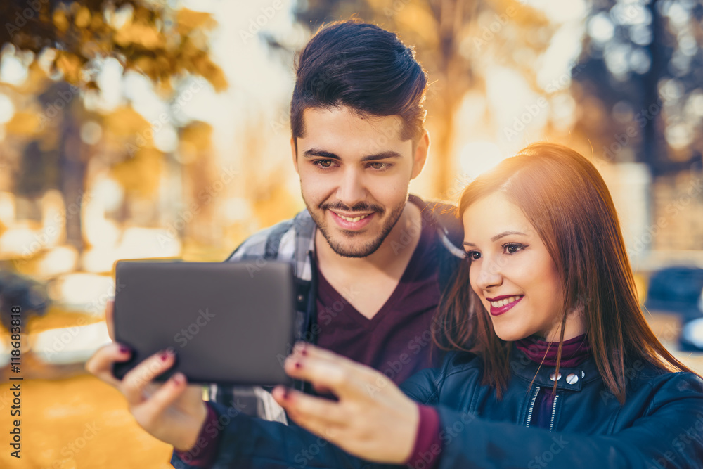Young couple in love lifestyle outdoor using tablet at the park Young couple in love lifestyle outdoor using tablet at the park