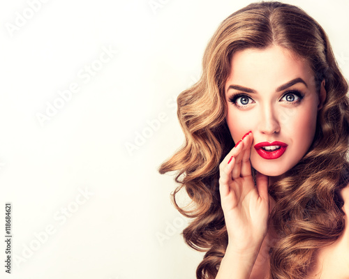 Beautiful girl with bright makeup and curly hair   telling   a secret .Portrait  young happy woman model   Expressive facial expressions