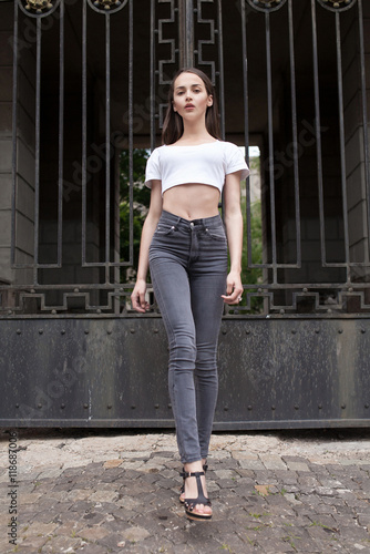 Beautiful girl with freckles and long hair in the street. Lifestyle outdoor portrait. woman in black jeans and white shirt. Fashion street shot.