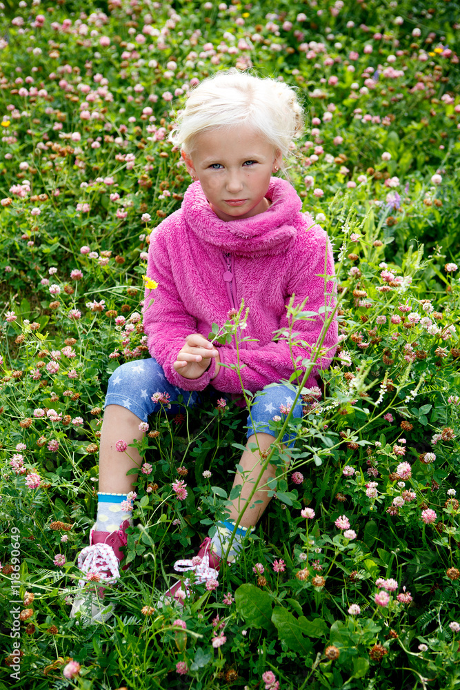 Portrait of a beautiful girl outdoors sitting on grass with flowers Portrait of a beautiful girl outdoors sitting on grass with flowers