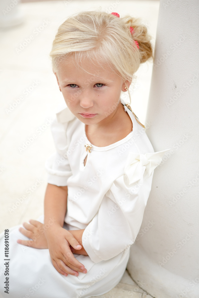 Portrait of beautiful little girl in a white dress near the columns Portrait of beautiful little girl in a white dress near the columns