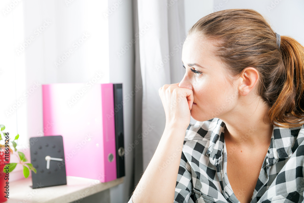 Desperate and worried woman in home office looking at window Desperate and worried woman in home office looking at window