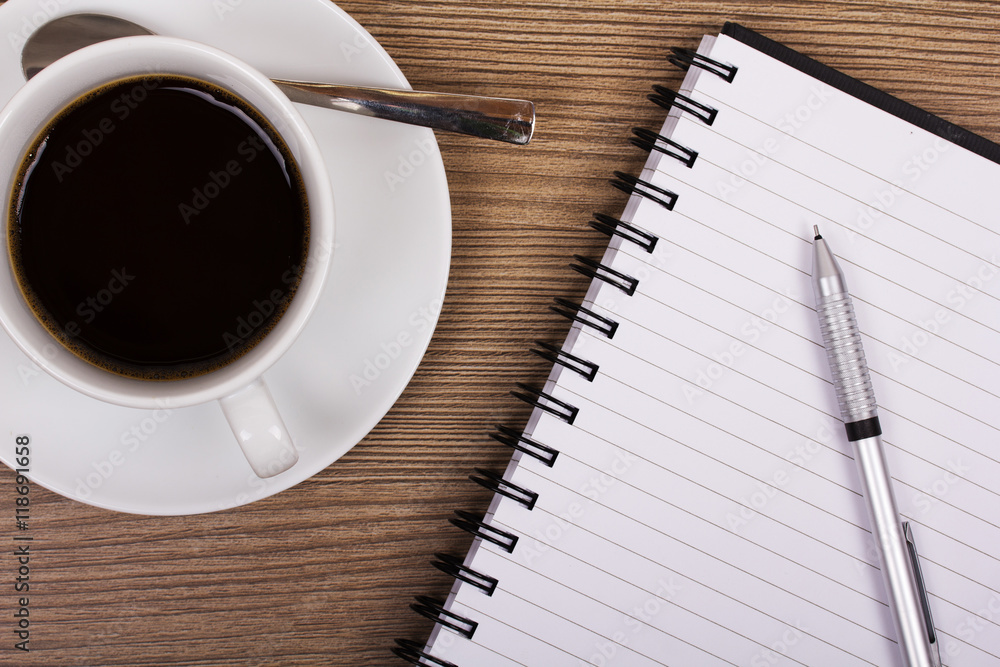 Cup of black coffee and notebook on wooden surface Cup of black coffee and notebook on wooden surface