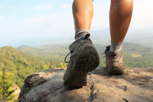 hiker legs climbing at mountain peak rock