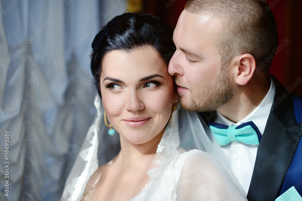 Wedding couple indoors is hugging each other. Beautiful model girl in white dress. Man in suit. Beauty bride with groom. Female and male portrait. Woman with lace veil. Cute lady and handsome guy Wedding couple indoors is hugging each other. Beautiful model girl in white dress. Man in suit. Beauty bride with groom. Female and male portrait. Woman with lace veil. Cute lady and handsome guy