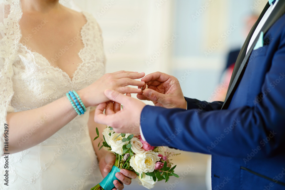 Beauty bride and handsome groom are wearing rings each other. Wedding  couple on the marriage ceremony.
