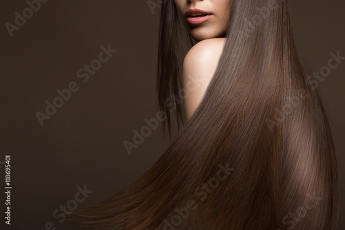 Fototapeta Beautiful brunette girl in move with a perfectly smooth hair, and classic make-up