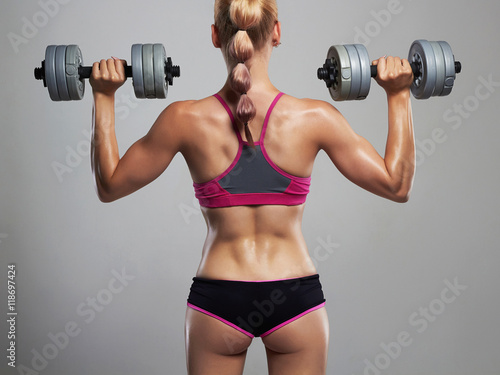 athletic bodybuilder young woman with dumbbells.blonde girl with muscles.gym