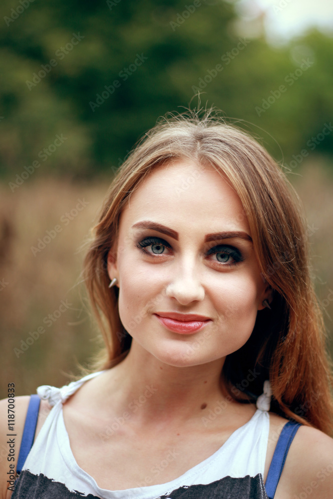 Portrait of a young cute woman. Outdoor portrait of a young cute blond woman with a long hair and autumn foliage background. Beautiful face eyes and lips. Charming smile Portrait of a young cute woman. Outdoor portrait of a young cute blond woman with a long hair and autumn foliage background. Beautiful face eyes and lips. Charming smile