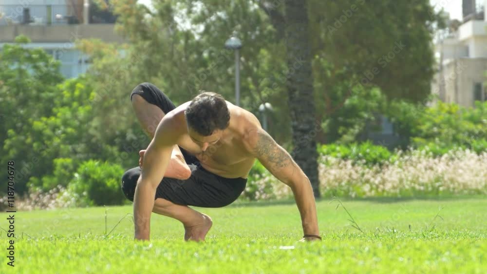A man on green grass in a sunny park yoga.