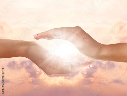 Female hands holding sunlight on sky background.