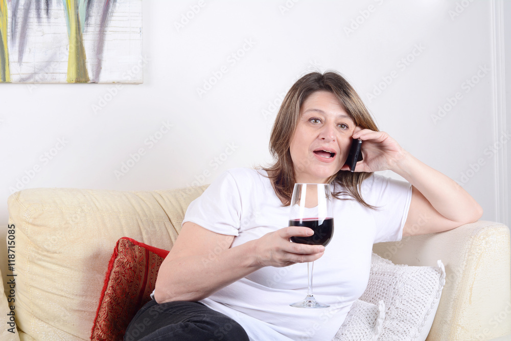 Woman with a glass of wine and talking on phone.
