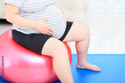 Pregnant woman does yoga exercise in home.