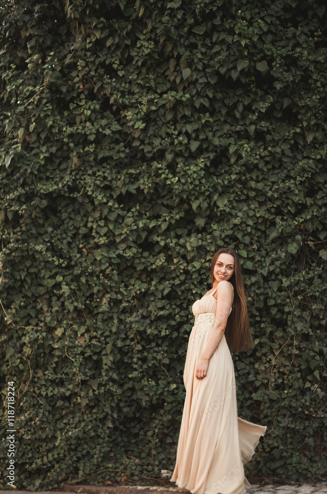 Beautiful girl, model near the wall of leaves and bushes in park Beautiful girl, model near the wall of leaves and bushes in park