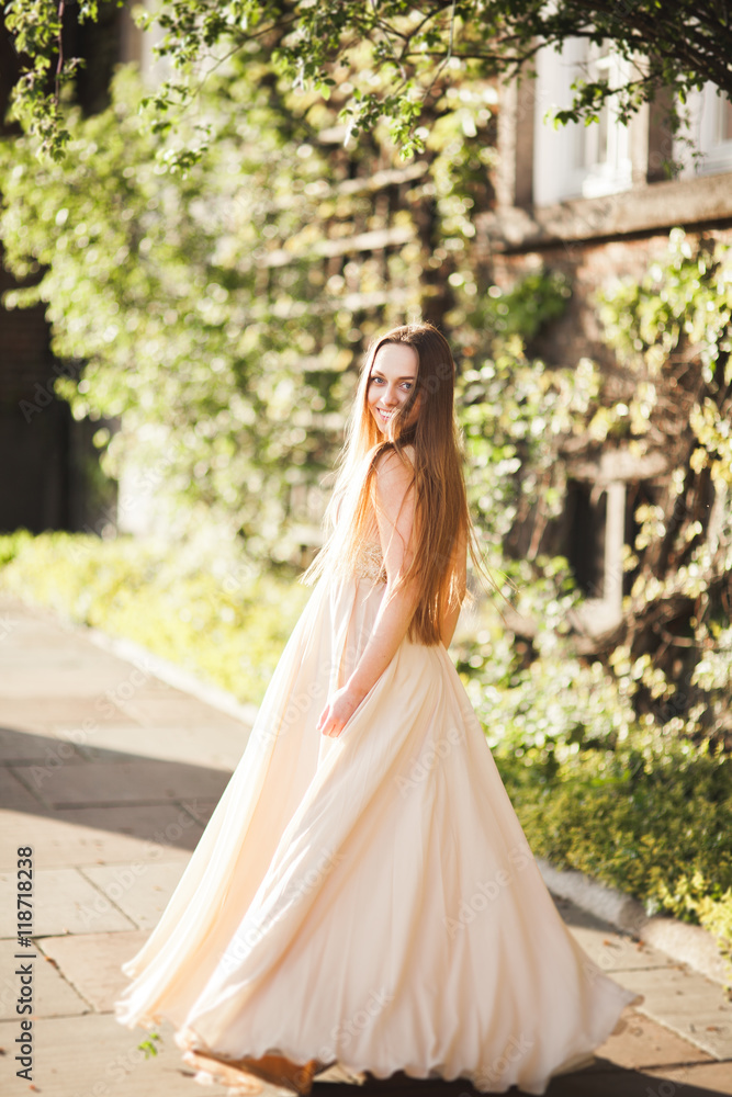 Attractive young woman with long dress enjoying her time outside in park sunset background