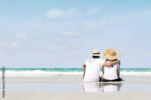 Young family sitting on warm sand by a sea