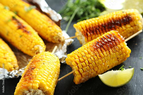 Tasty grilled corn on black wooden table