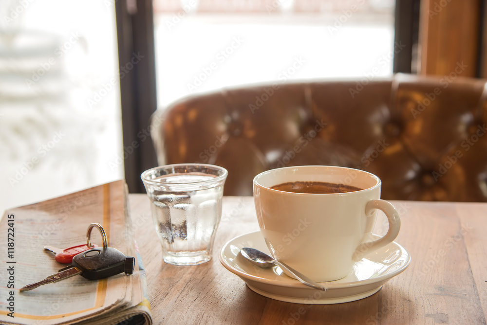 White coffee cup , blurred newspaper, car key and glass water o White coffee cup , blurred newspaper, car key and glass water o