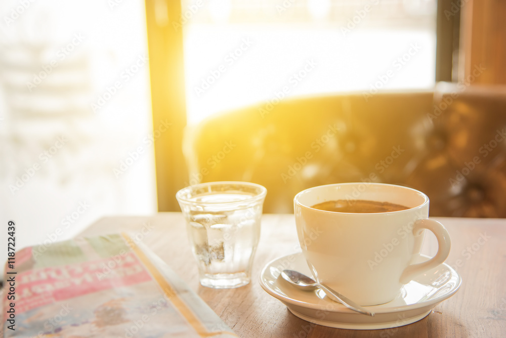 White coffee cup ,Newspaper and glass water on wooden table. White coffee cup ,Newspaper and glass water on wooden table.