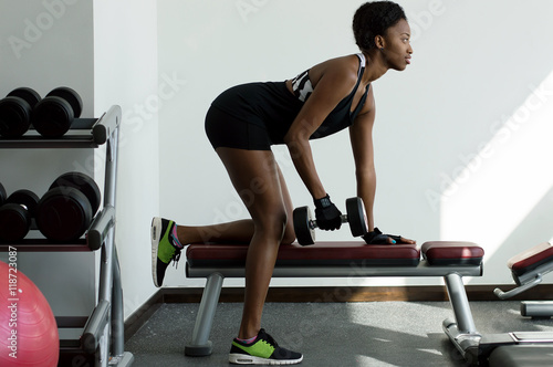 Young african woman doing exercises with weights. Healthy lifestyle concept