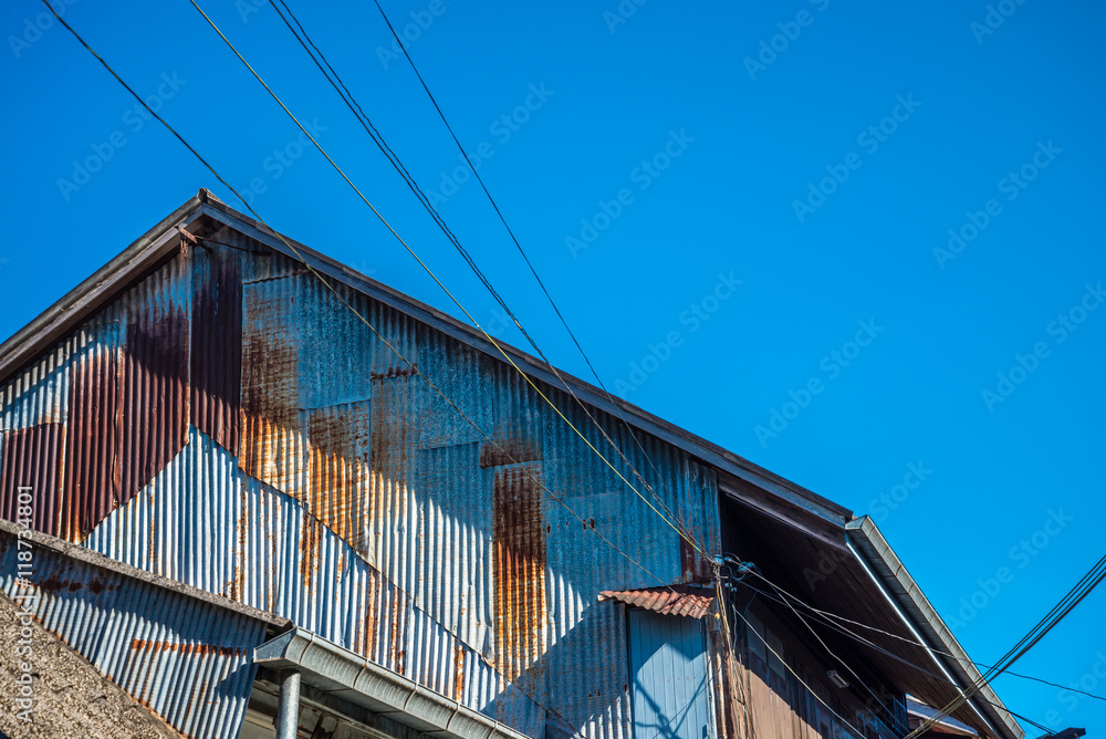 Obraz premium Old rusty galvanized iron plate house in countryside sunny day blue sky background.