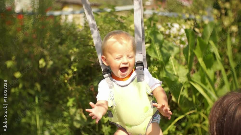 Young pretty mother swinging young son in jumpers Young pretty mother swinging young son in jumpers