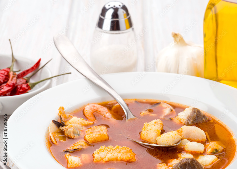 delicious plate of seafood soup with spoon in modern wooden