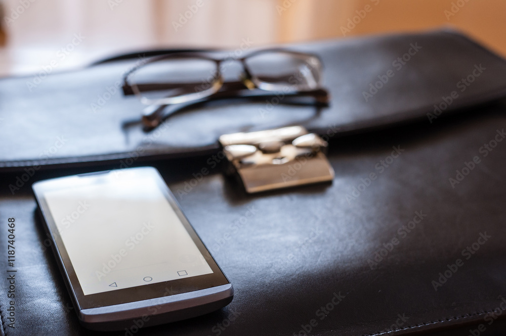 Businessman accessories: black briefcase, smartphone and glasses Businessman accessories: black briefcase, smartphone and glasses