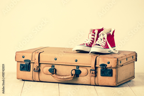 Obraz na plátne Sneakers on top of an old brown suitcase with a retro effect