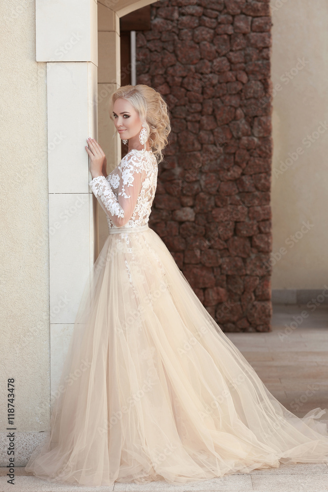 Obraz premium Elegant bride in fashion wedding dress posing by the wall. Attra