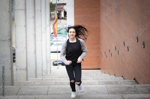 Chica joven morena subiendo y bajando feliz las escaleras en la ciudad. Modelo morena posando en las escaleras. © Trepalio