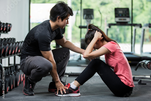 Trainer holding a woman in the leg exercise by Sit-up