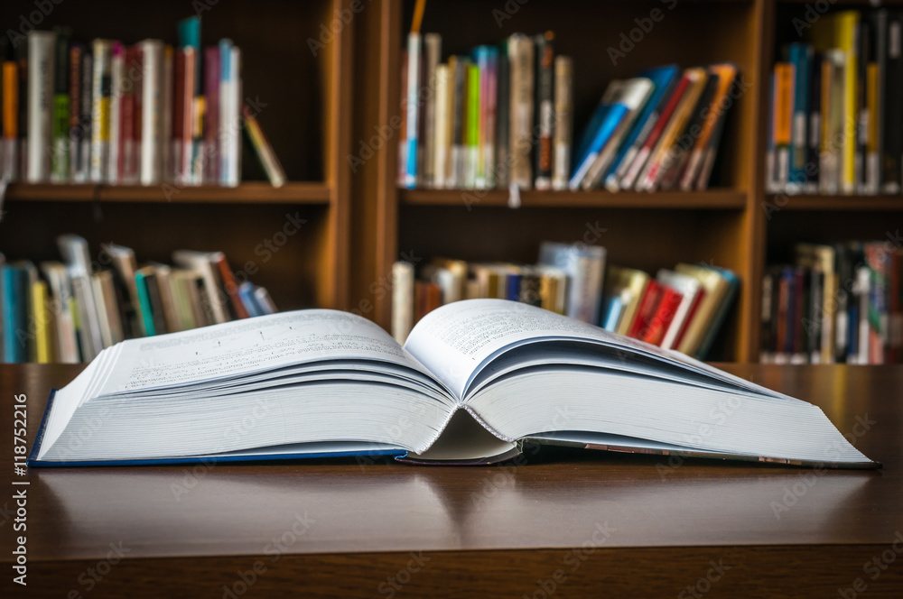 Open book on the table in a library and bookshelf Open book on the table in a library and bookshelf