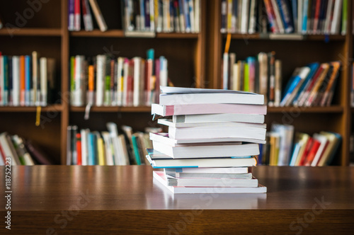 Pile of books in a library and bookshelf