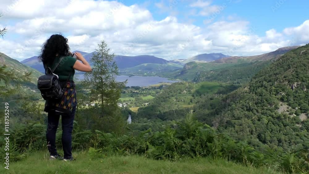 Woman on mount taking picture with smartphone of the beautiful Derwentwater lake scenery in Lake District, England Woman on mount taking picture with smartphone of the beautiful Derwentwater lake scenery in Lake District, England