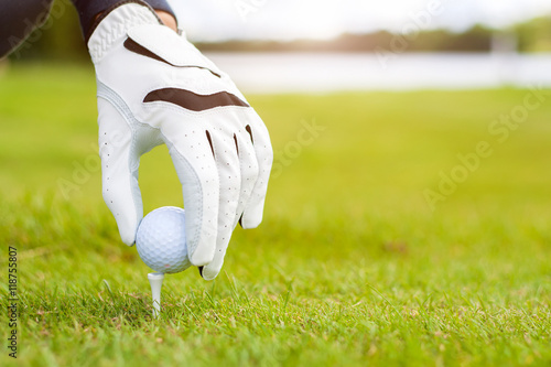 Hand hold golf ball with tee on course, close-up
