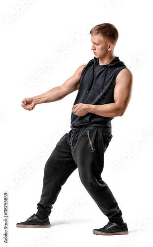 Side view of handsome muscled young man pulling something isolated on white background