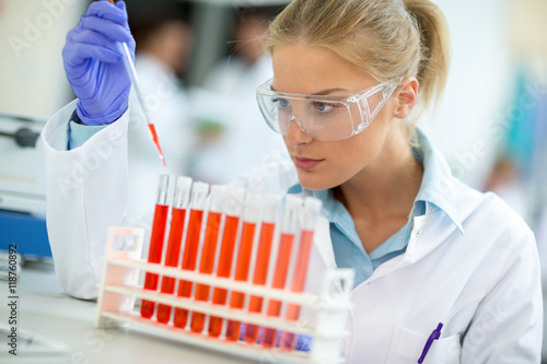 Attractive female chemical assistant work with test tubes