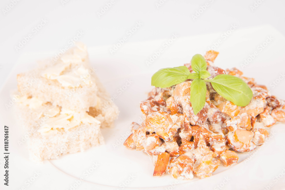 Sauteed chanterelle with cream and garlic and some white bread on a plate decorated with basil Sauteed chanterelle with cream and garlic and some white bread on a plate decorated with basil