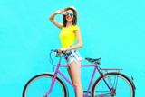 Fashion pretty smiling woman on retro pink bicycle over colorful