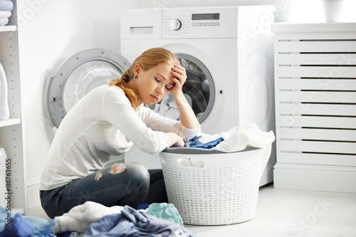 Fotografie tired unhappy woman housewife  fold clothes into the washing mac