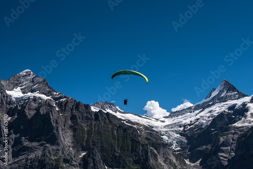 Gleitschirmpilot über den Alpen vor blauem Himmel