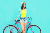 Pretty smiling woman with bicycle over colorful blue background