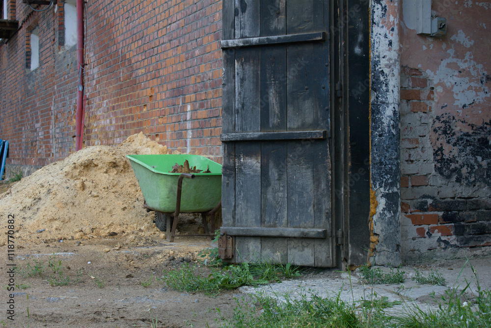 Naklejka premium Old barn with open gate and wheels 