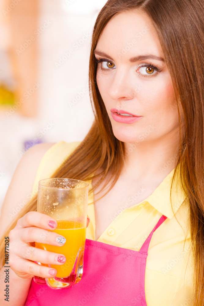 Woman in kitchen drinking fresh orange juice Woman in kitchen drinking fresh orange juice