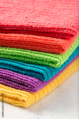 pile of bathroom towels in rainbow colors, isolated over a white wood background, close up, vertical