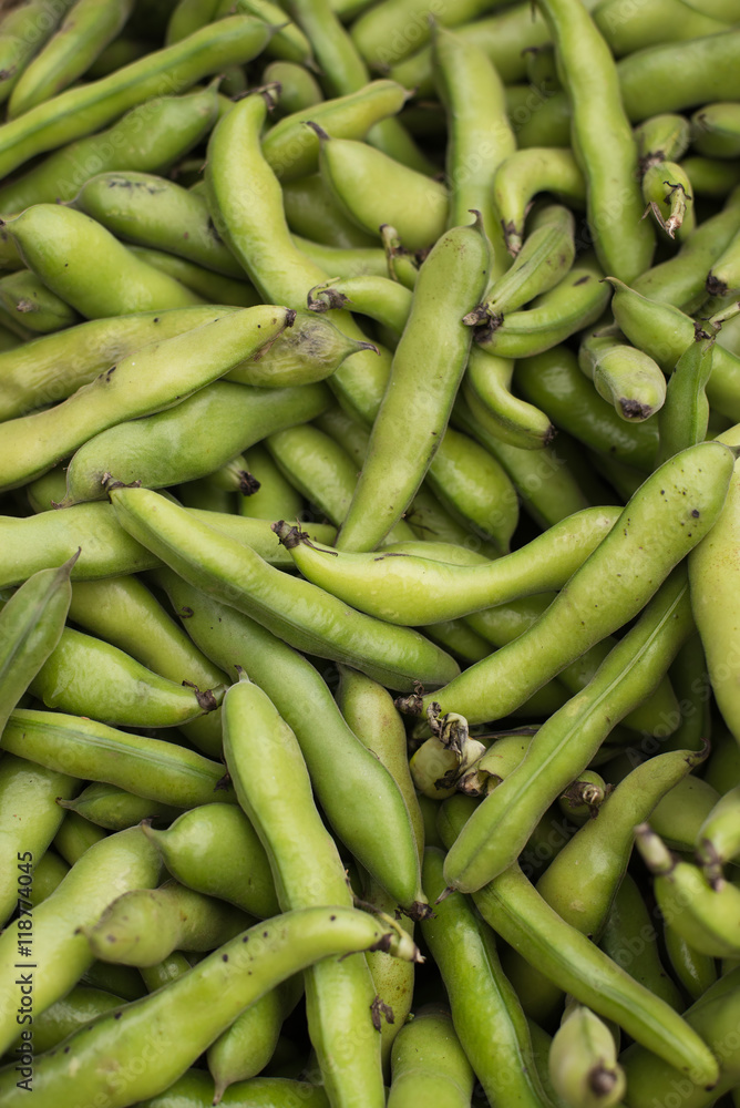 fresh and organic fava or broad beans at farmers market. food as background, vertical.